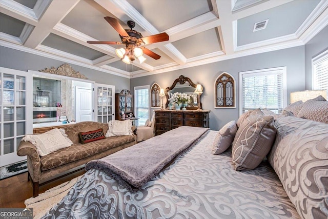 bedroom featuring visible vents, ornamental molding, coffered ceiling, and wood finished floors