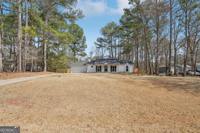 ranch-style house featuring driveway, a front lawn, fence, an attached garage, and a chimney