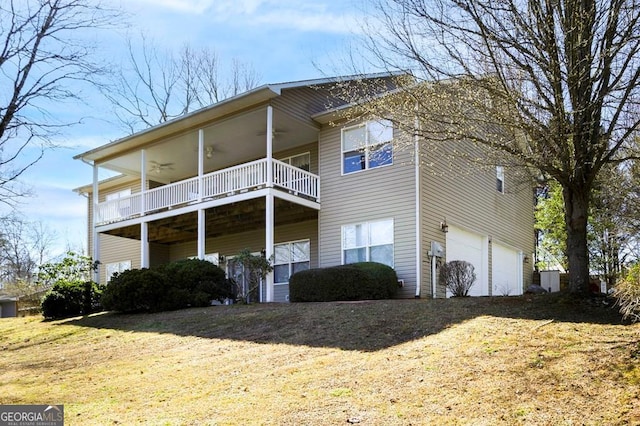 back of property with a yard, an attached garage, and a ceiling fan