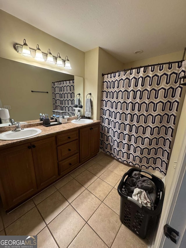 full bath featuring tile patterned flooring, double vanity, a textured ceiling, and a sink