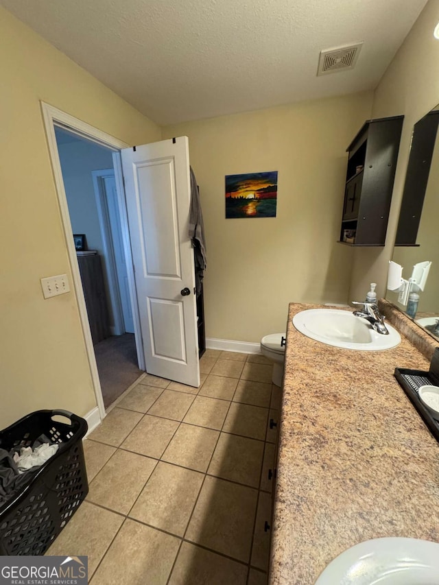 bathroom with tile patterned flooring, visible vents, double vanity, a textured ceiling, and a sink