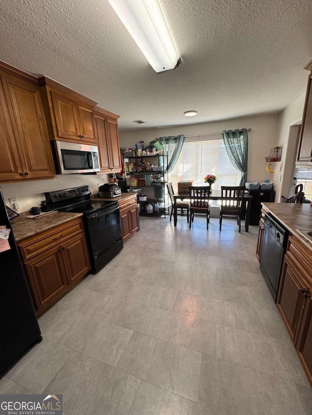 kitchen featuring black appliances, dark countertops, and brown cabinets