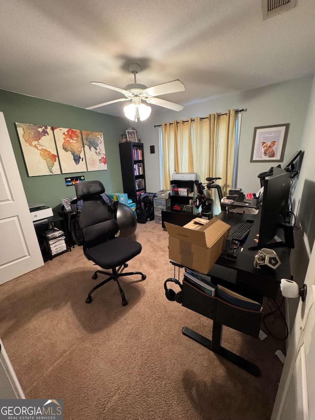 home office with carpet flooring, a ceiling fan, visible vents, and a textured ceiling