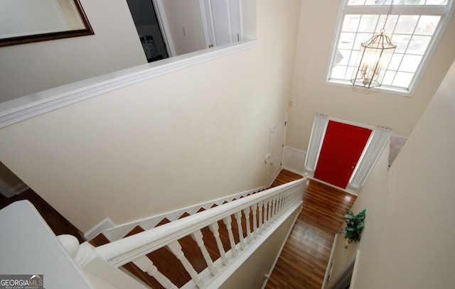 staircase with a chandelier, baseboards, and wood finished floors