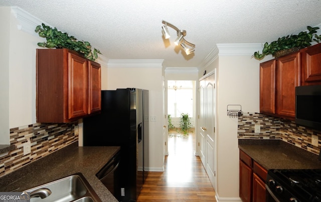 kitchen with ornamental molding, dark countertops, a textured ceiling, wood finished floors, and appliances with stainless steel finishes