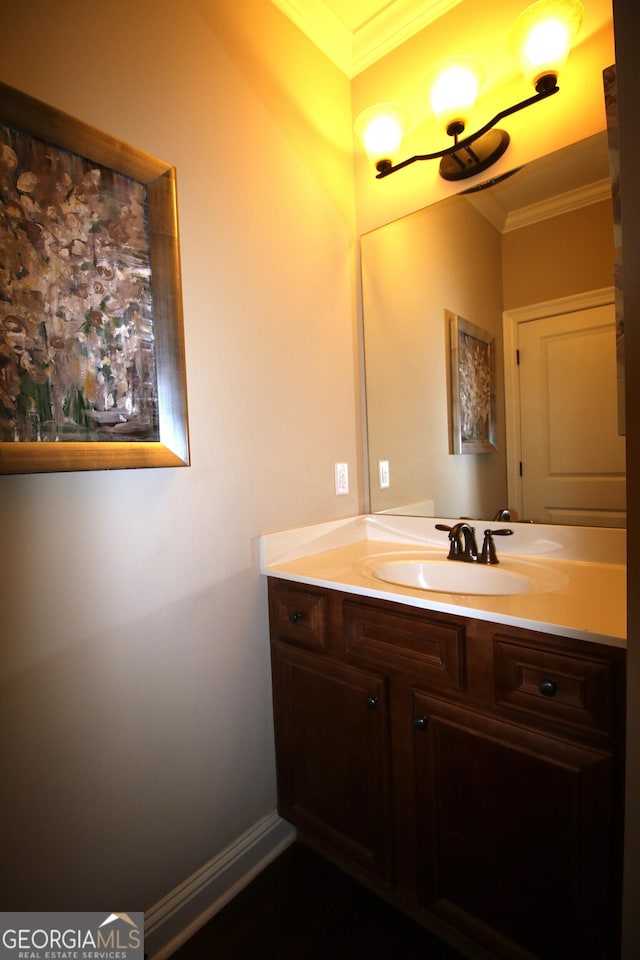 bathroom featuring baseboards, ornamental molding, and vanity