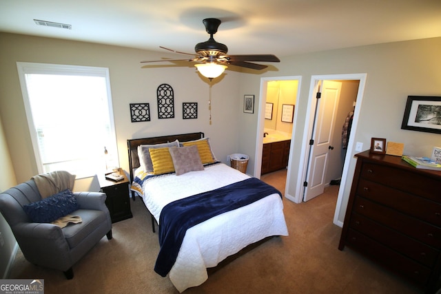 bedroom featuring visible vents, light colored carpet, and ensuite bathroom