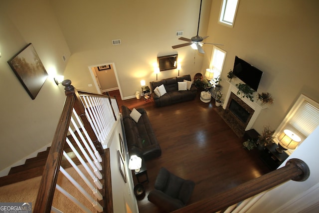 living area with a high ceiling, wood finished floors, visible vents, and a premium fireplace