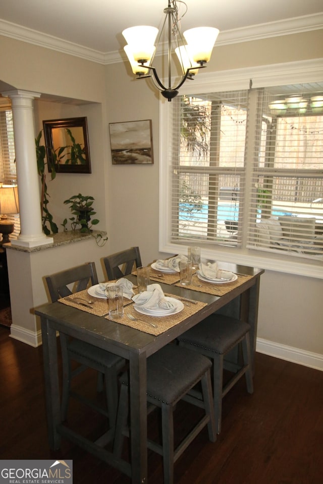 dining space featuring dark wood finished floors, a healthy amount of sunlight, ornate columns, and ornamental molding