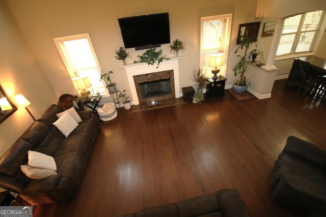 living room with a premium fireplace, decorative columns, baseboards, and wood finished floors