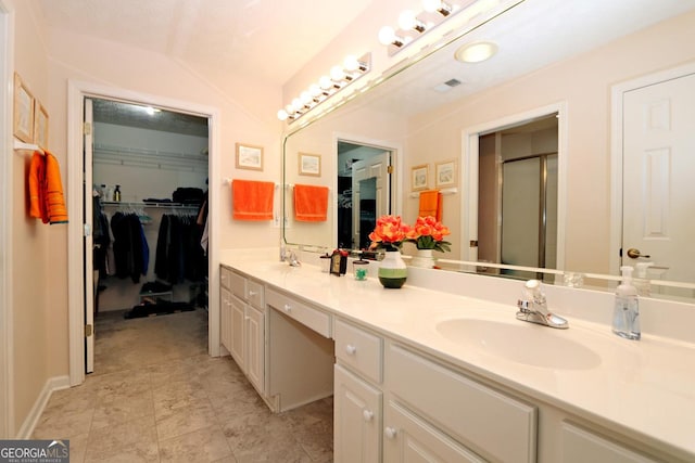 full bath featuring a sink, a spacious closet, a shower stall, and double vanity