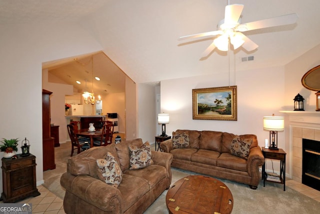 living room featuring visible vents, a tiled fireplace, vaulted ceiling, light carpet, and ceiling fan with notable chandelier