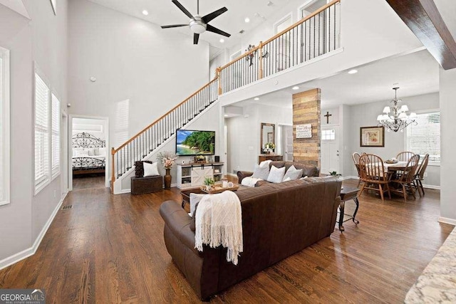 living room with baseboards, wood finished floors, stairs, and ceiling fan with notable chandelier