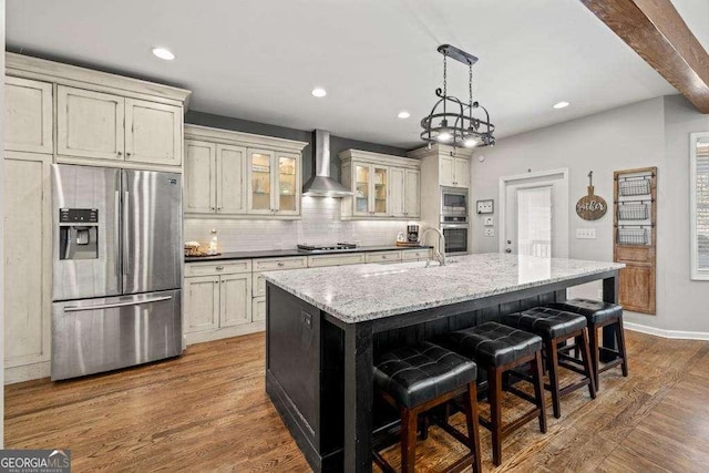 kitchen with backsplash, dark wood-type flooring, appliances with stainless steel finishes, and wall chimney range hood