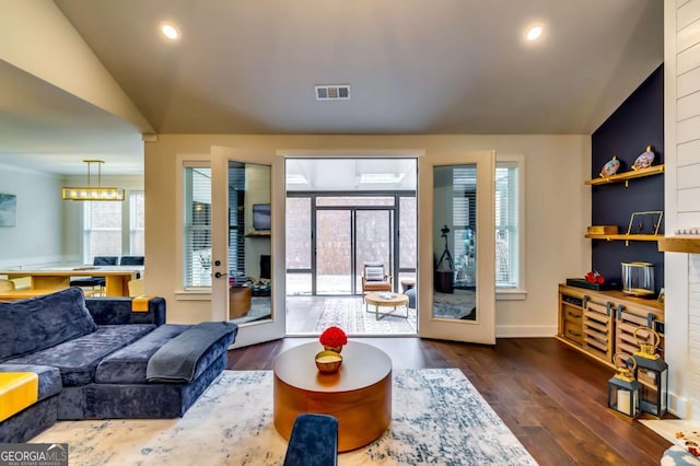 living area featuring lofted ceiling, recessed lighting, wood finished floors, and visible vents