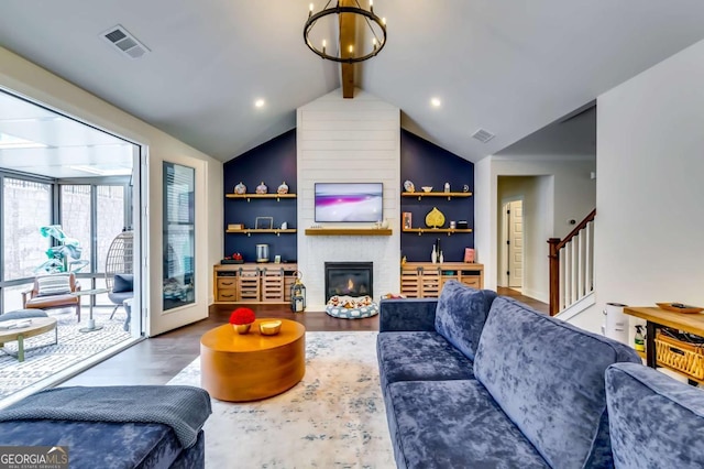 living area with visible vents, a large fireplace, stairway, lofted ceiling with beams, and wood finished floors