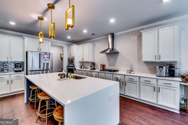 kitchen with dark wood-type flooring, a sink, wall chimney range hood, stainless steel appliances, and light countertops