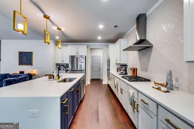 kitchen with blue cabinets, visible vents, a sink, stainless steel appliances, and wall chimney range hood