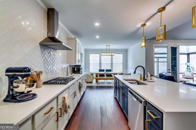 kitchen with blue cabinetry, a sink, stainless steel appliances, wall chimney exhaust hood, and light countertops