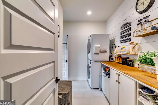 laundry room with recessed lighting, cabinet space, and stacked washer / dryer