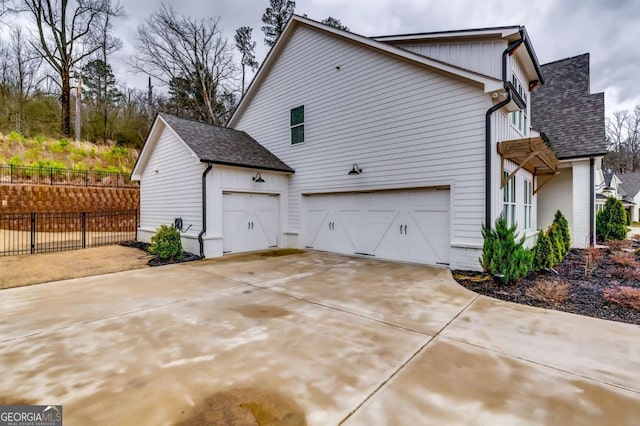 view of home's exterior with brick siding, board and batten siding, an attached garage, and fence