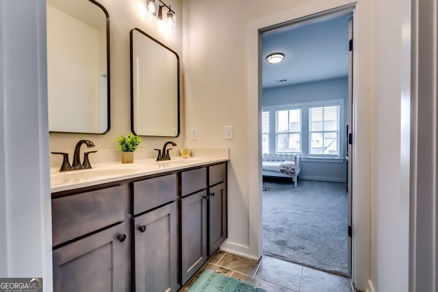 ensuite bathroom featuring a sink, baseboards, ensuite bath, and double vanity