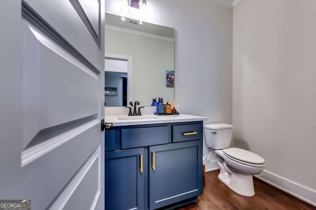 half bathroom with toilet, vanity, baseboards, and wood finished floors