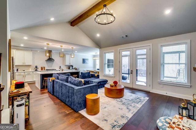 living area featuring visible vents, dark wood-type flooring, french doors, beamed ceiling, and a chandelier