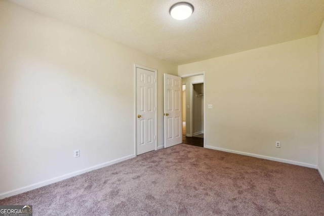 carpeted empty room featuring baseboards and a textured ceiling