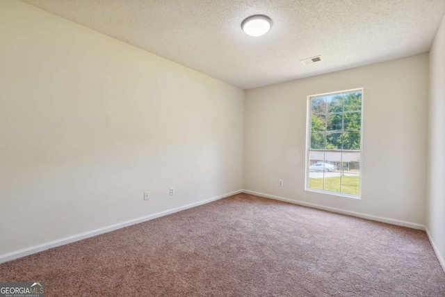 carpeted spare room with visible vents, a textured ceiling, and baseboards