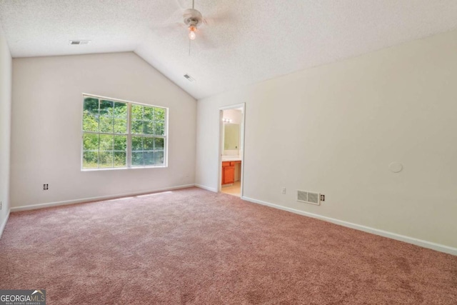 unfurnished bedroom with vaulted ceiling, carpet flooring, visible vents, and a textured ceiling