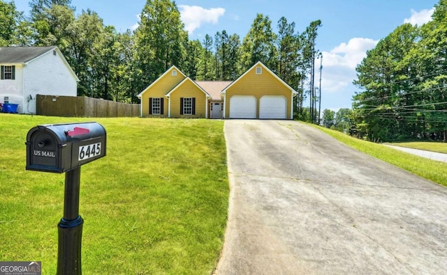 view of front facade with a garage, driveway, a front lawn, and fence