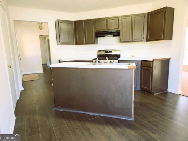 kitchen with under cabinet range hood, stainless steel range with gas cooktop, dark wood-style floors, and light countertops