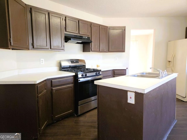 kitchen with under cabinet range hood, white fridge with ice dispenser, stainless steel gas range, light countertops, and dark wood-style flooring