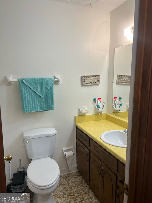 bathroom with baseboards, toilet, and vanity