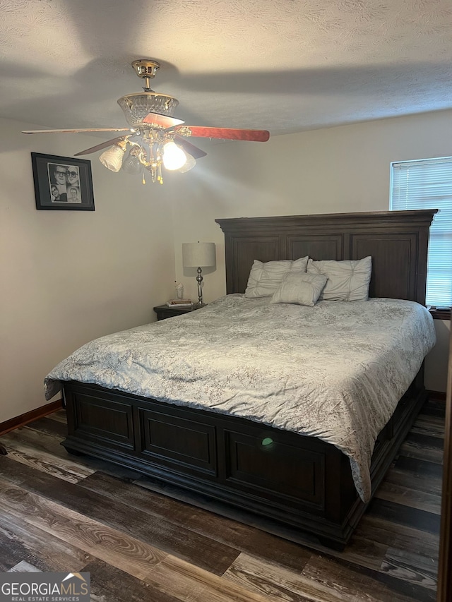 bedroom featuring ceiling fan, dark wood-type flooring, baseboards, and a textured ceiling