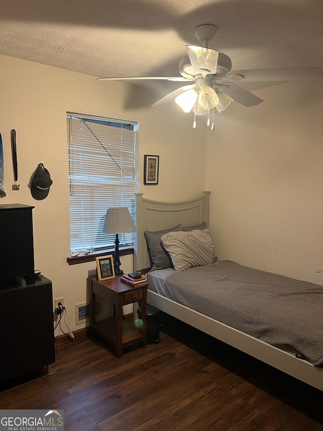 bedroom featuring visible vents, a textured ceiling, ceiling fan, and wood finished floors