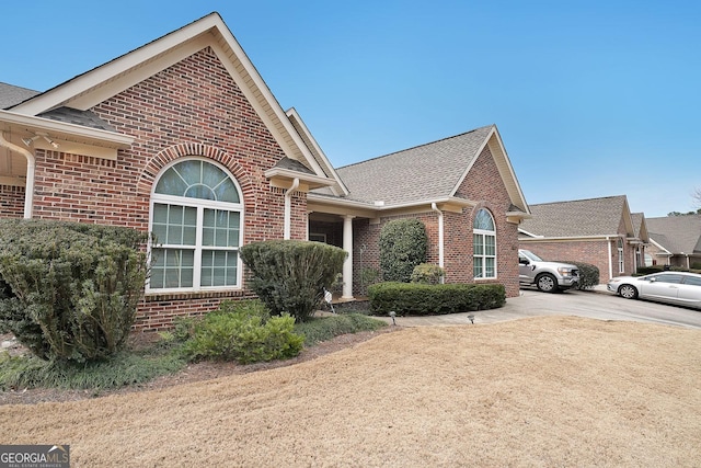 view of front of property with brick siding, concrete driveway, and a shingled roof