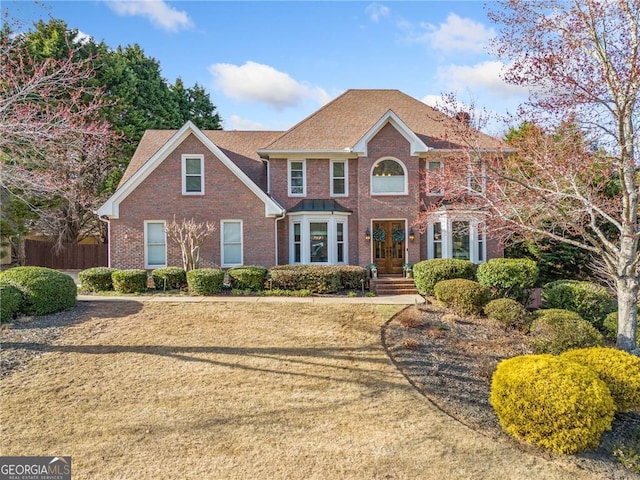 view of front of house featuring brick siding and fence