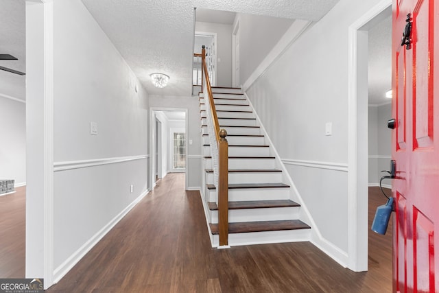 stairs with visible vents, wood finished floors, baseboards, and a textured ceiling