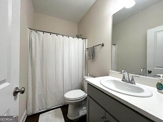 bathroom featuring a shower with shower curtain, toilet, and vanity