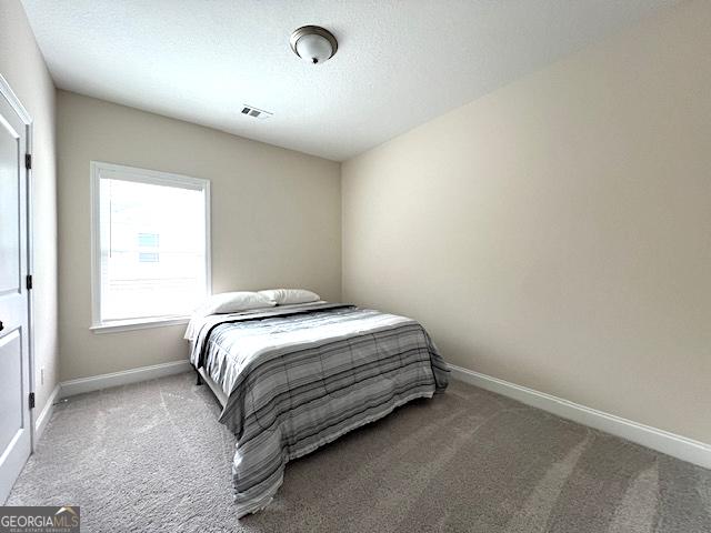 bedroom featuring visible vents, baseboards, a textured ceiling, and carpet flooring