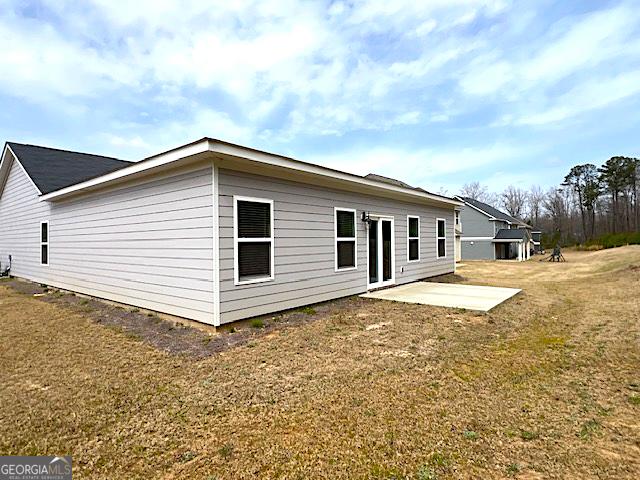 rear view of house featuring a lawn and a patio area