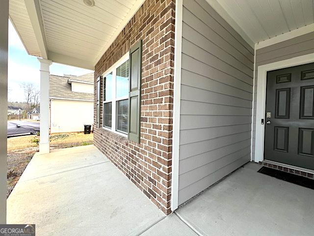 property entrance with brick siding and a porch