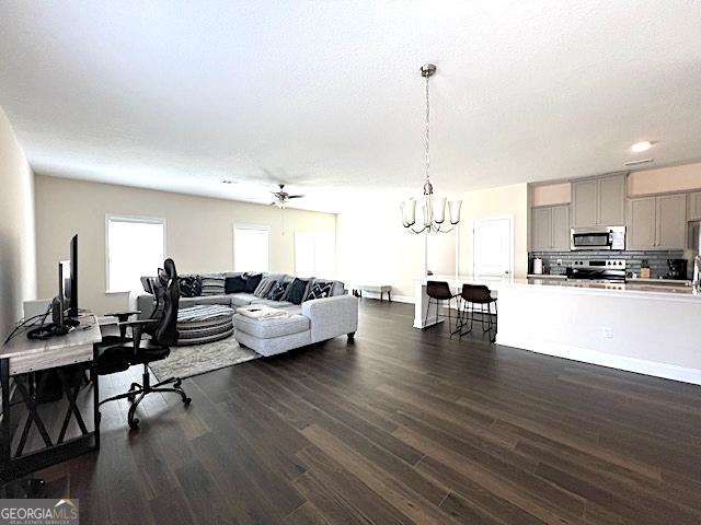 living area with dark wood finished floors, baseboards, and an inviting chandelier