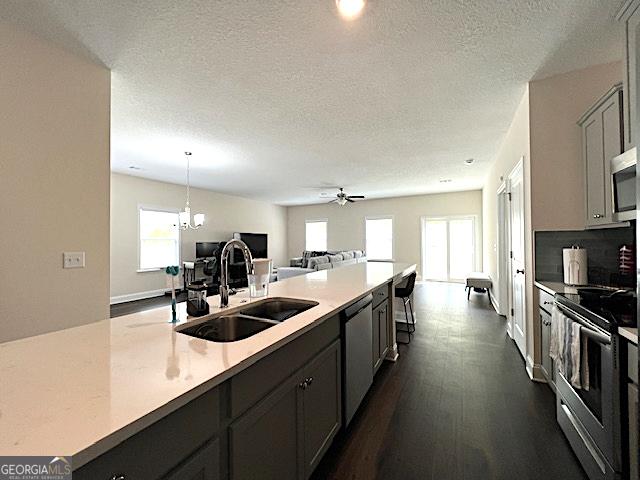 kitchen featuring stainless steel appliances, a sink, light countertops, open floor plan, and a wealth of natural light