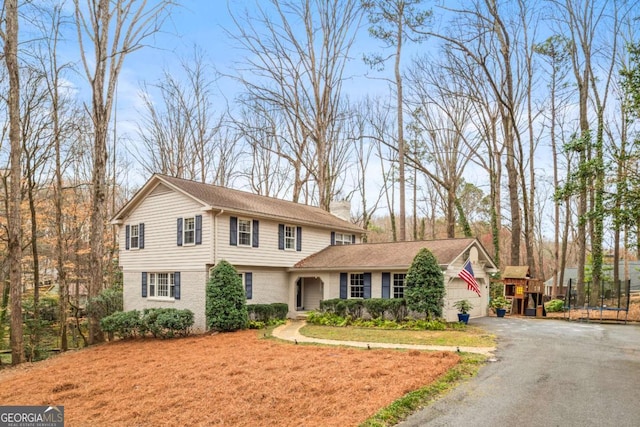 view of front of home featuring a chimney, a front lawn, a garage, aphalt driveway, and brick siding