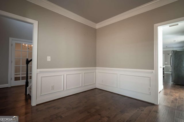 unfurnished room with dark wood finished floors, visible vents, wainscoting, and ornamental molding