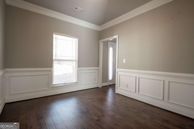 empty room with visible vents, dark wood-type flooring, a wainscoted wall, and ornamental molding