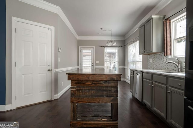 kitchen with dark wood finished floors, ornamental molding, a sink, gray cabinetry, and stainless steel dishwasher